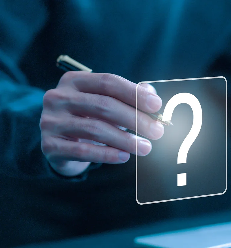 Close-up of a hand holding a pen near a glowing question mark icon on a transparent screen.