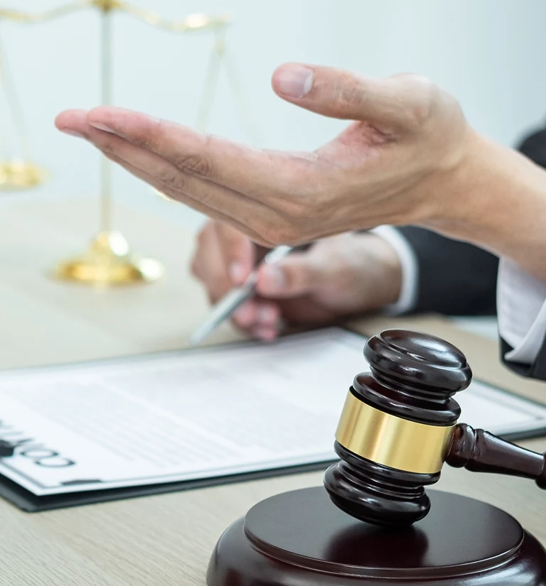 Close-up of a judge’s gavel, hand gesture, and contract document on a desk.