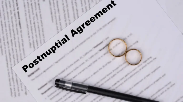 Postnuptial agreement document with two gold wedding rings and a black pen on top.