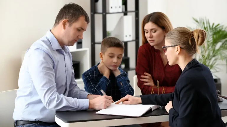 Professional woman in glasses explaining documents to a man, woman, and child at office.